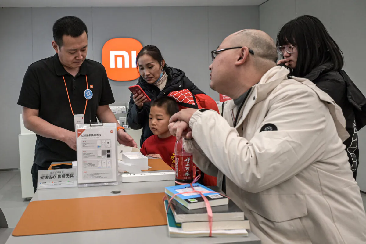 A Xiaomi sales representative helps customers at a shopping mall in Beijing on Jan. 15, 2025, amid a sluggish economy. (Jade Gao/AFP)