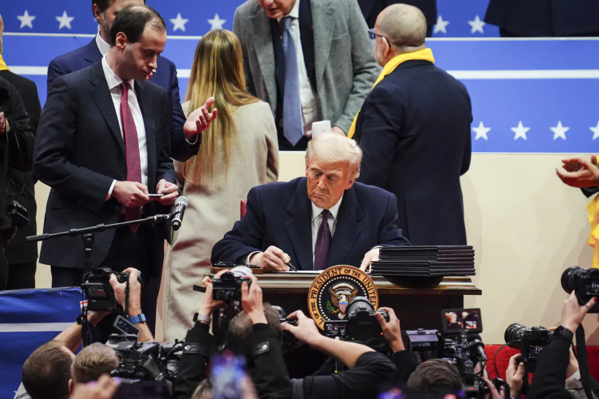U.S. President Donald Trump signs executive orders at the Capital One Arena in Washington on Jan. 20, 2025. (Madalina Vasiliu/The Epoch Times)