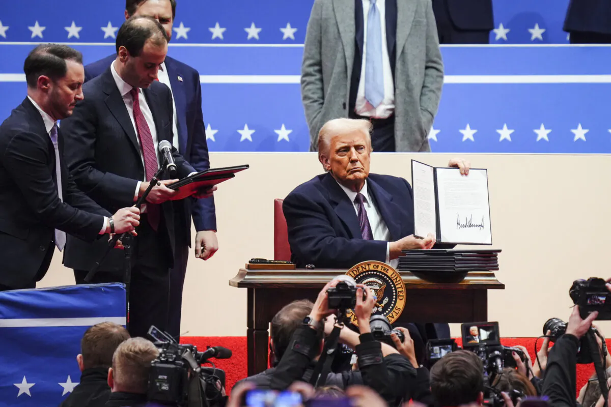 U.S. President Donald Trump signs executive orders at the Capital One Arena in Washington on Jan. 20, 2025. (Madalina Vasiliu/The Epoch Times)