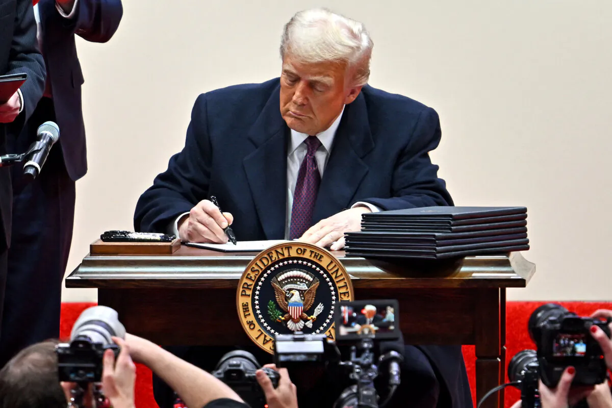 U.S. President Donald Trump signs executive orders during the inaugural parade inside Capital One Arena, in Washington, on Jan. 20, 2025. (Angela Weiss/AFP)