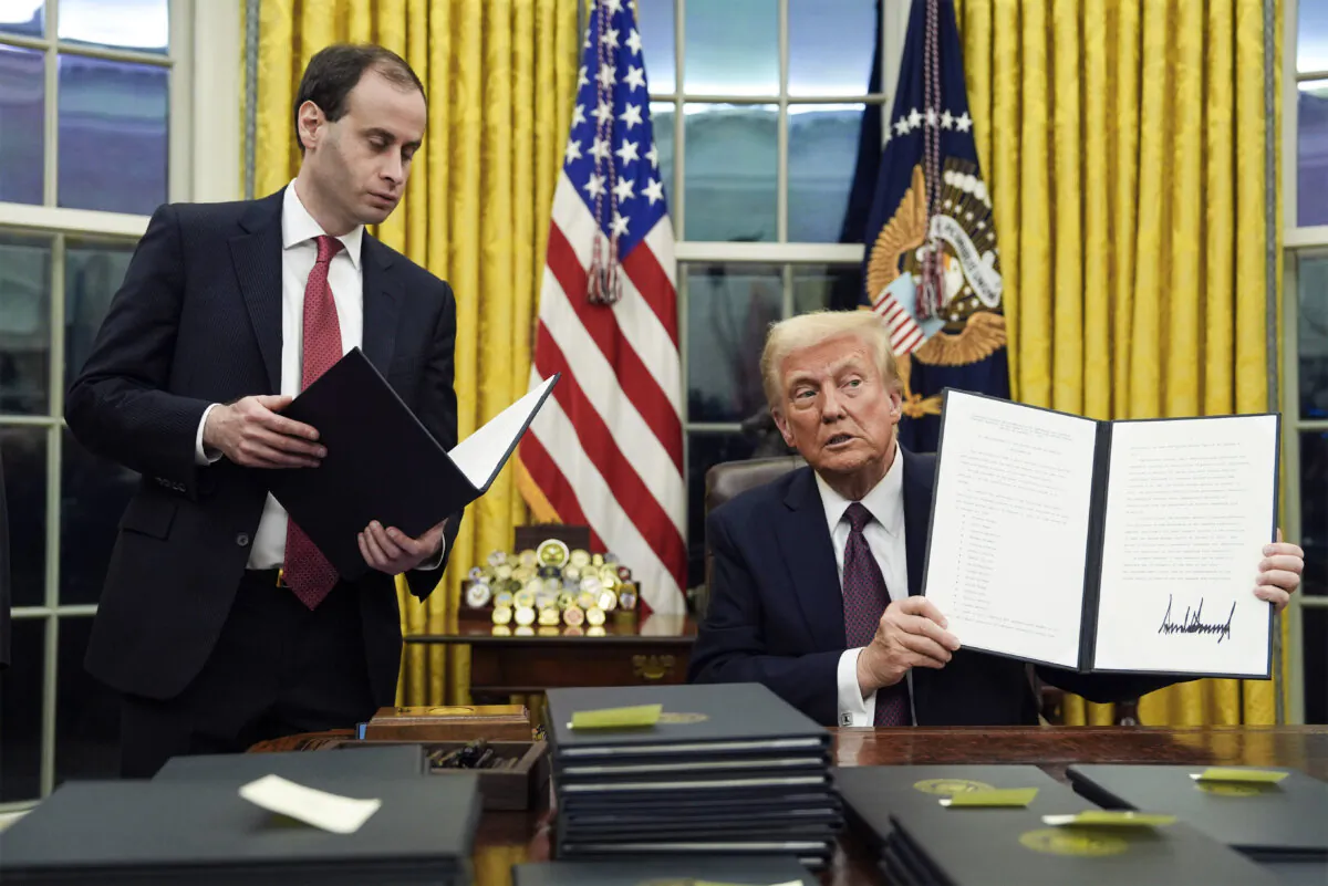 President Donald Trump holds up an executive order commuting sentences for people convicted of Jan. 6 offenses in the Oval Office on Jan. 20. (Evan Vucci/AP Photo)