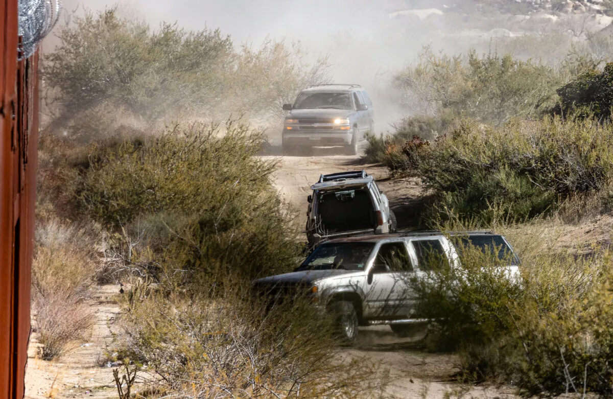 Mexican cartel members driving SUVs race to an open gap in the U.S. border wall near Jacomba, Calif., on Dec. 6, 2023. (John Fredricks/The Epoch Times)