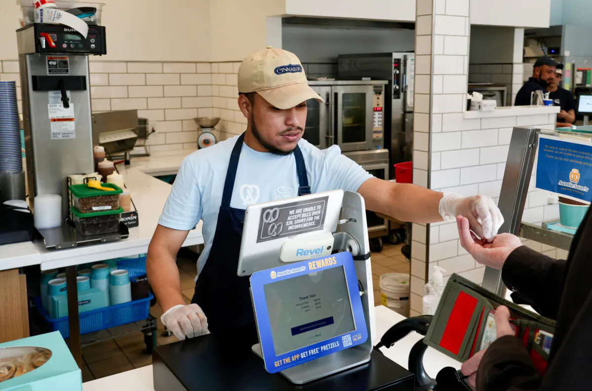 An employee collects payment at an Auntie Anne's and Cinnabon store in Livermore, Calif., on March 28, 2024. He's among hundreds of thousands of California fast-food workers who will be paid at least $20 per hour starting on April 1, 2025. (AP Photo/Terry Chea)
