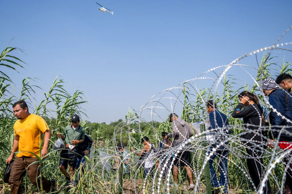 Illegal immigrants from El Salvador walk through brush alongside the banks of the Rio Grande after crossing into the United States in Eagle Pass, Texas, on May 21, 2022. (Brandon Bell/Getty Images)