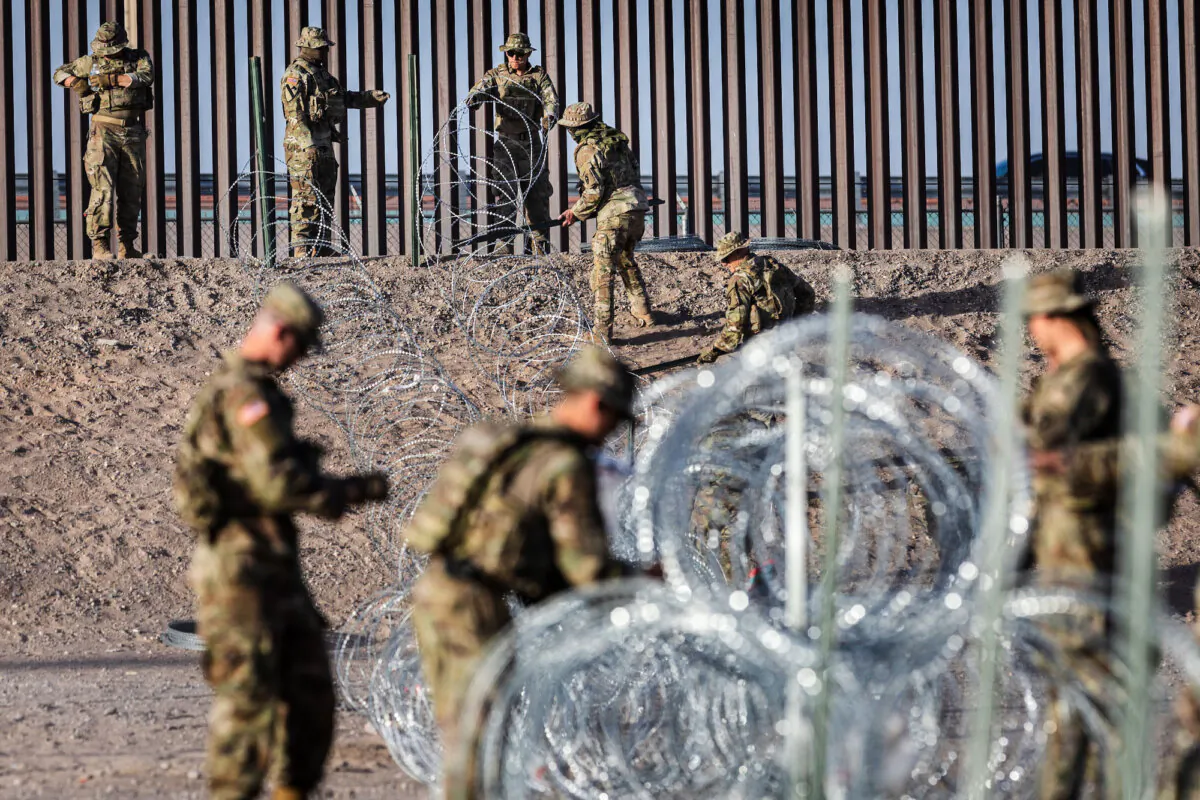 Texas National Guard soldiers uncoil concertina wire near the U.S.–Mexico border fence in El Paso, Texas, on May 10, 2023. (John Moore/Getty Images)