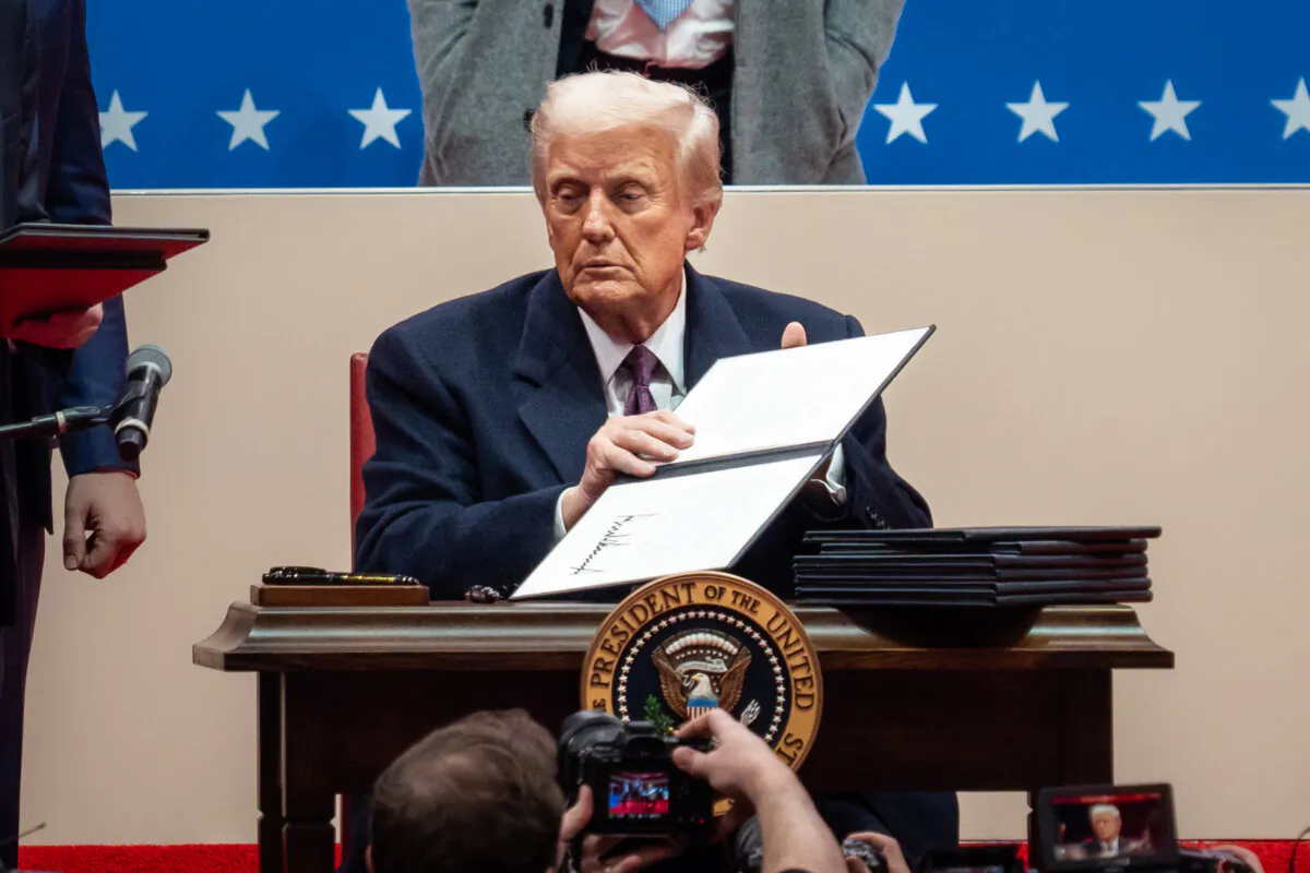 President Donald Trump signs executive orders at the Capital One Arena in Washington on Jan. 20, 2025. (Madalina Vasiliu/The Epoch Times)
