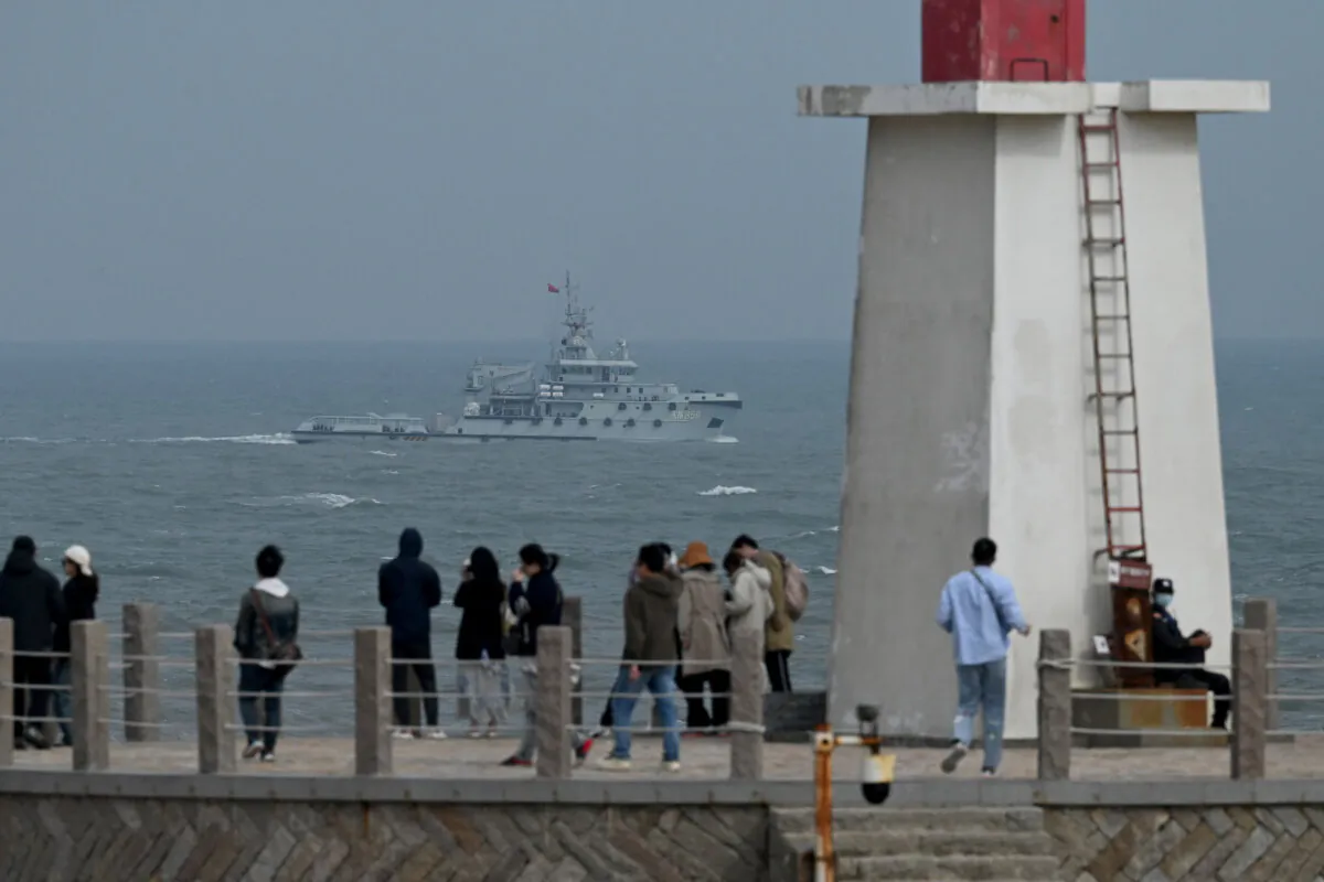 A Chinese navy tugboat sails in the Taiwan Strait, past tourists on Pingtan Island, the closest point to Taiwan, in China's southeast Fujian Province, on April 7, 2023. (Greg Baker/AFP via Getty Images)