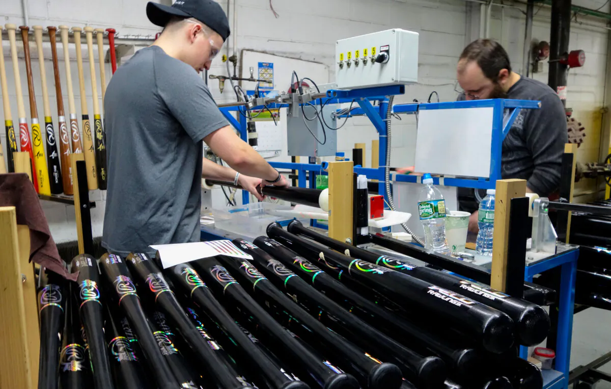 A worker affixes labels to a baseball bat on the production line at Rawlings Sporting Goods in Dolgeville, N.Y., on March 1, 2017. (William Edwards/AFP via Getty Images)