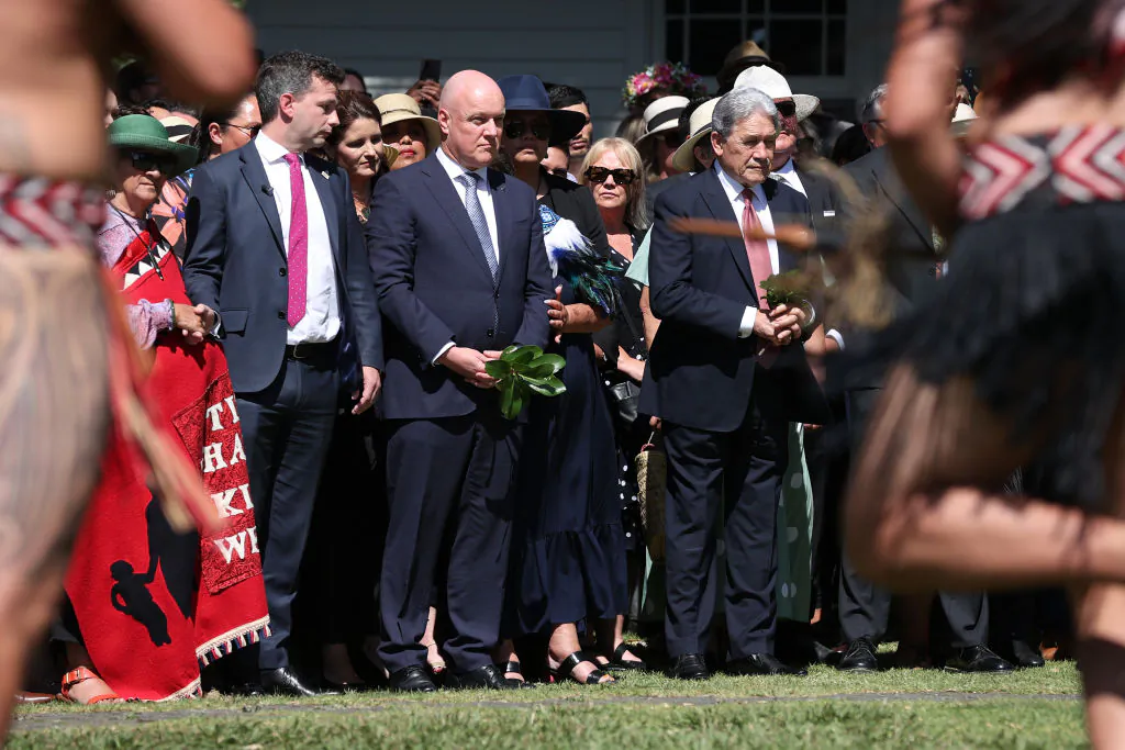 New Zealand government representatives including Prime Minister Christopher Luxon (C) ACT leader David Seymour (L) and New Zealand First leader Winston Peters (R) are welcomed onto Te Whare Rūnanga during a pōwhiri in Waitangi, New Zealand on Feb. 5, 2024. (Fiona Goodall/Getty Images)