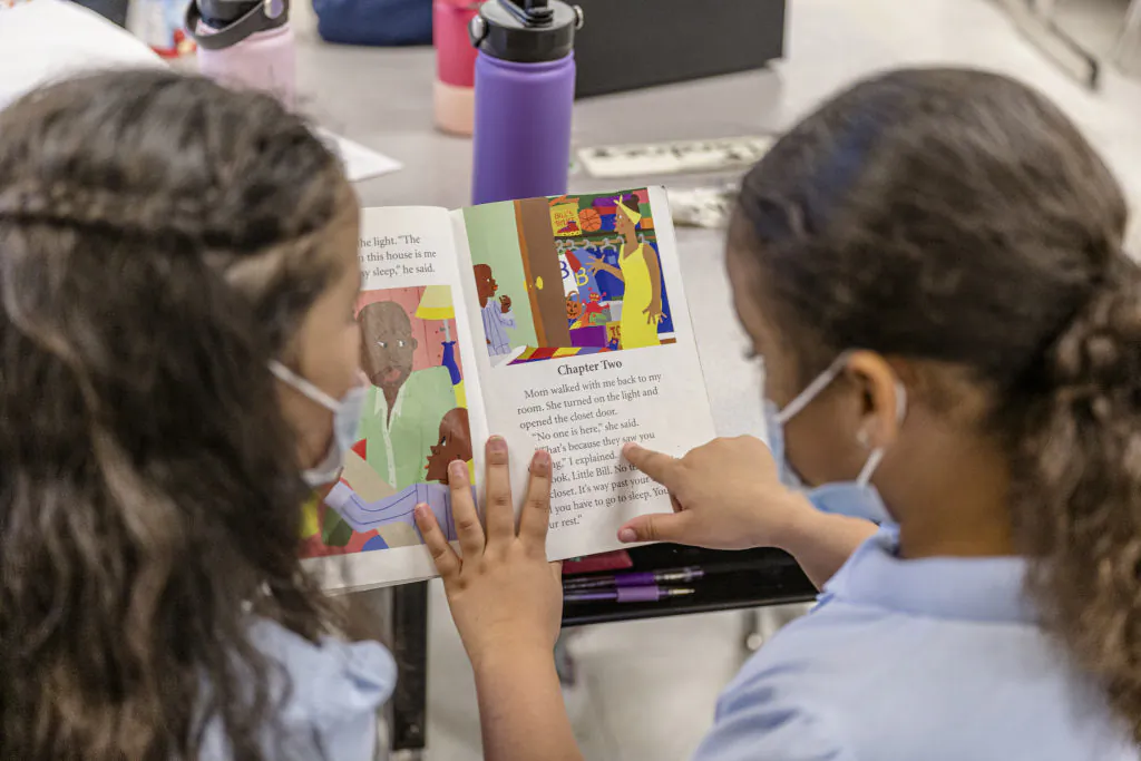 Two girls read a book together during a lesson at Carter Traditional Elementary School in Louisville, Ky., on Jan. 24, 2022. (Jon Cherry/Getty Images)