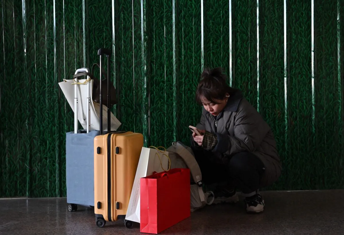A woman checks her phone as people return to their hometowns for the Chinese Lunar New Year reunions at a train station in Beijing on Jan. 20, 2025. (Adek Berry/AFP via Getty Images)