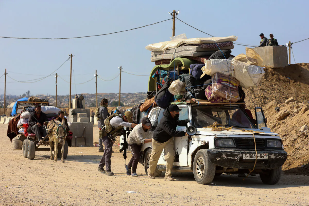 Men help to push a loaded vehicle as displaced Palestinians cross a checkpoint manned by U.S. and Egyptian security at the Netzarim corridor on their way from the south to the northern parts of the Gaza Strip, on Salah al-Din road in central Gaza, on Jan. 29, 2025. (Omar Al-Qattaa / AFP via Getty Images)