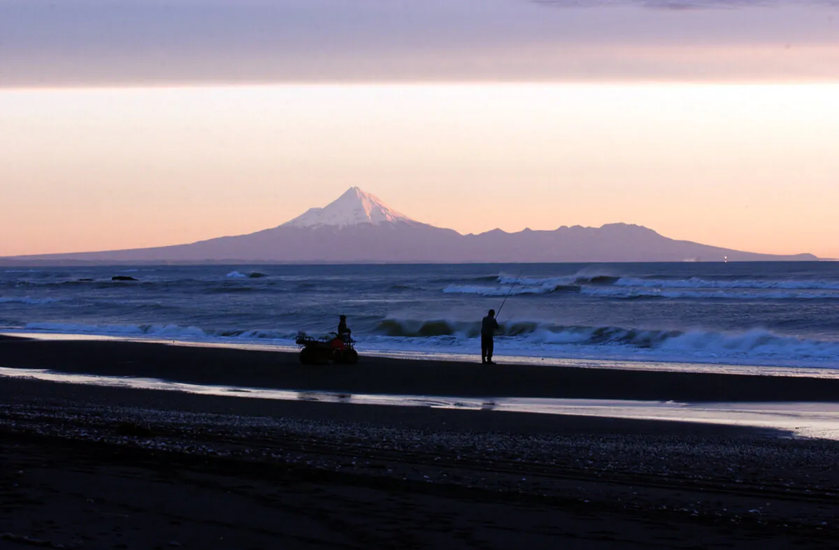 Fishermen cast a line in the surf at the Mokau river mouth on the TaranakiWaikato boarder, under the shadow of Mt Taranaki. (Ross Land/Getty Images)