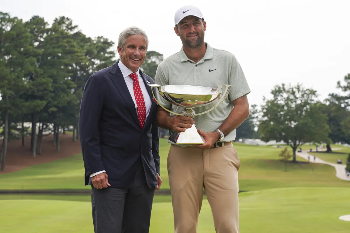 PGA Tour Commissioner Jay Monahan, left, poses with Scottie Scheffler and the FedExCup Trophy after Scheffler won the final round of the Tour Championship golf tournament in Atlanta on Sept. 1, 2024. (Jason Allen/AP Photo)