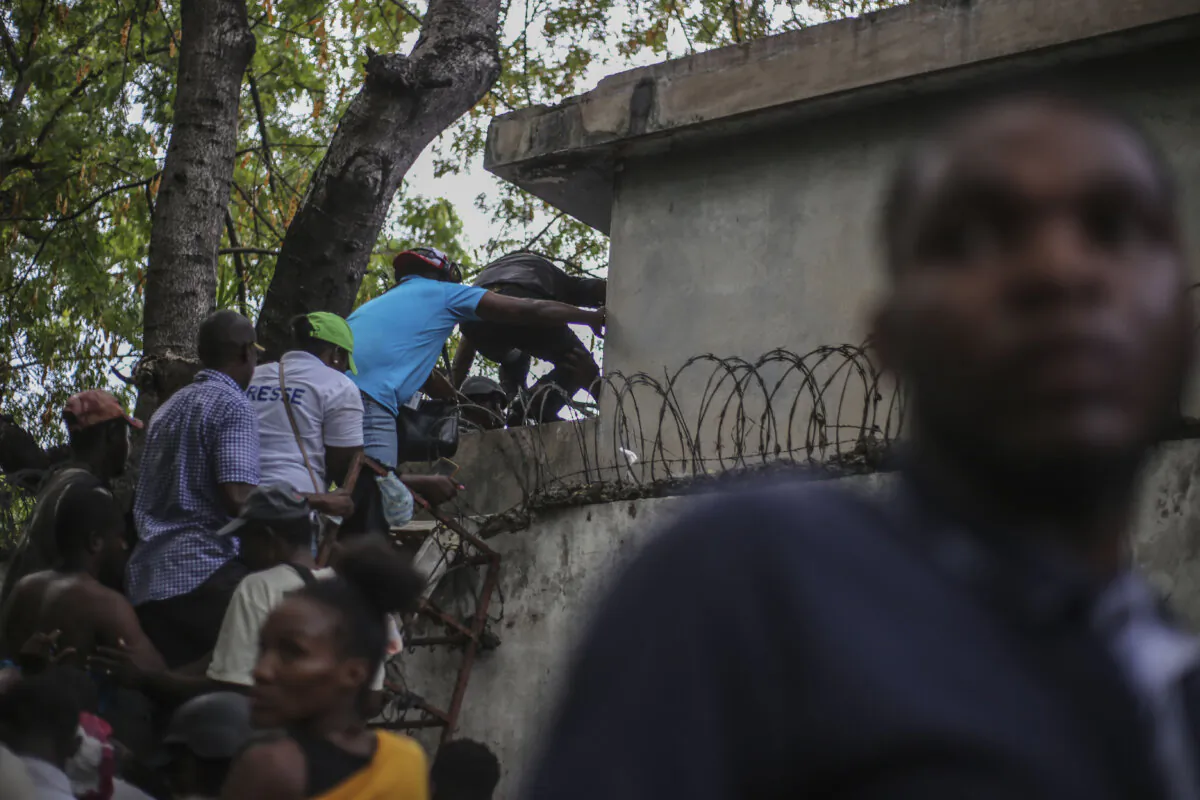 Journalists climb up a wall to take cover from gunfire, after being shot at by armed gangs at the General Hospital in Port-au-Prince, Haiti, on  Dec. 24, 2024. (Jean Feguens Regala/AP Photo)