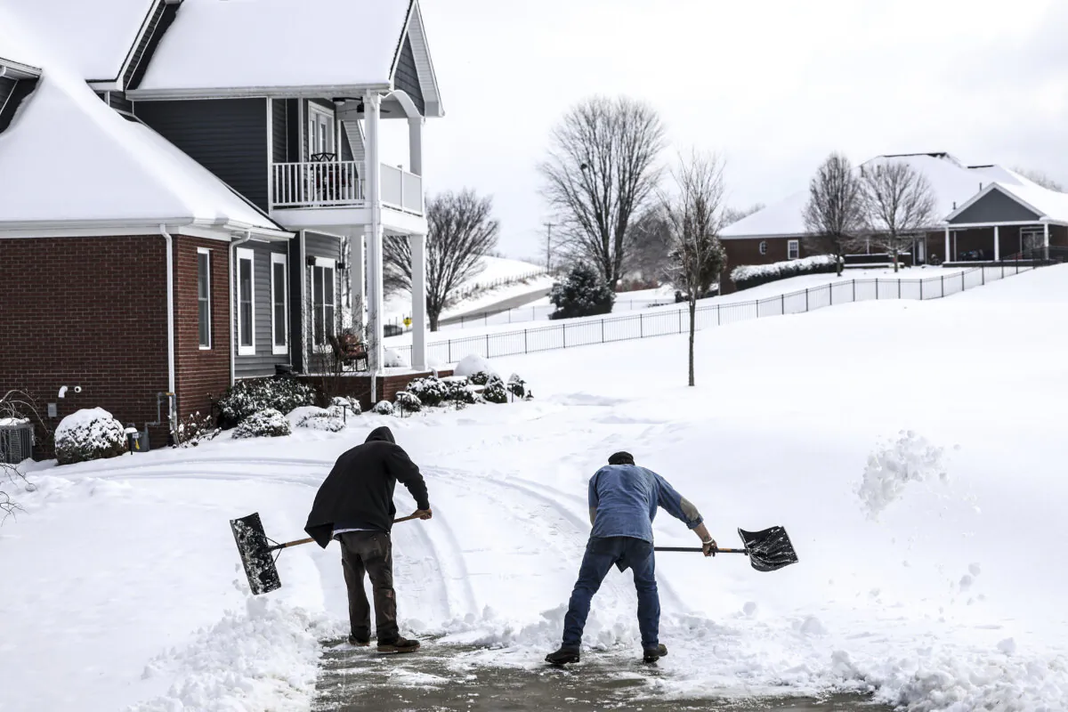 Joe Huff (L) and Kenny Braden with "The Yard Barber" work to clear snow from the driveway of a home in The Summit neighborhood in Owensboro, Ky., on Jan. 11, 2025. (Greg Eans/The Messenger-Inquirer via AP)