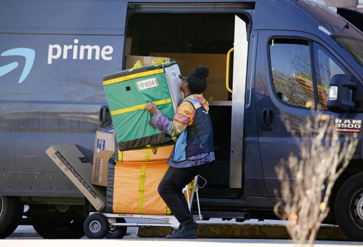 An Amazon Prime delivery person lifts packages while making a stop in Denver on Nov. 28, 2023. (AP Photo/David Zalubowski, File)