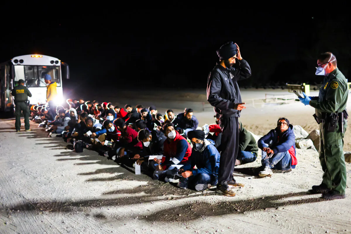 Illegal immigrants wait to board a U.S. Border Patrol bus to be taken for processing after crossing the border from Mexico, in Yuma, Ariz., on May 22, 2022. (Mario Tama/Getty Images)