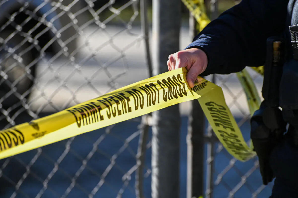 A law enforcement officer puts up police tape at a crime scene in an undated file photograph. (Samantha Laurey/AFP via Getty Images)