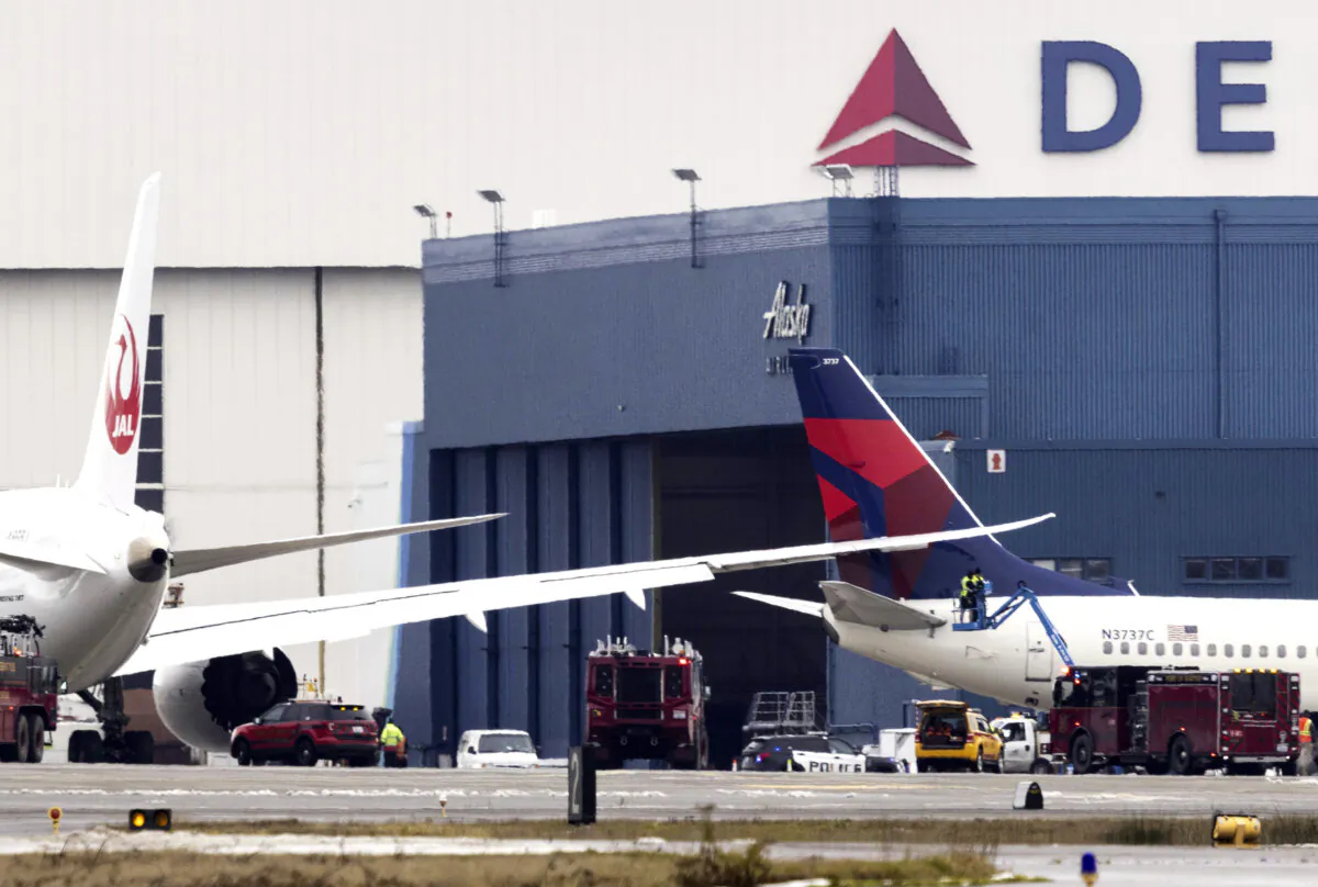 Workers on a lift check the area where the wing of a Japan Airlines jet went into the tail of a Delta Air Lines jet at the south end of a runway at Seattle-Tacoma International Airport in SeaTac, Wash., on Feb. 5, 2025. (Ellen M. Banner/The Seattle Times via AP)
