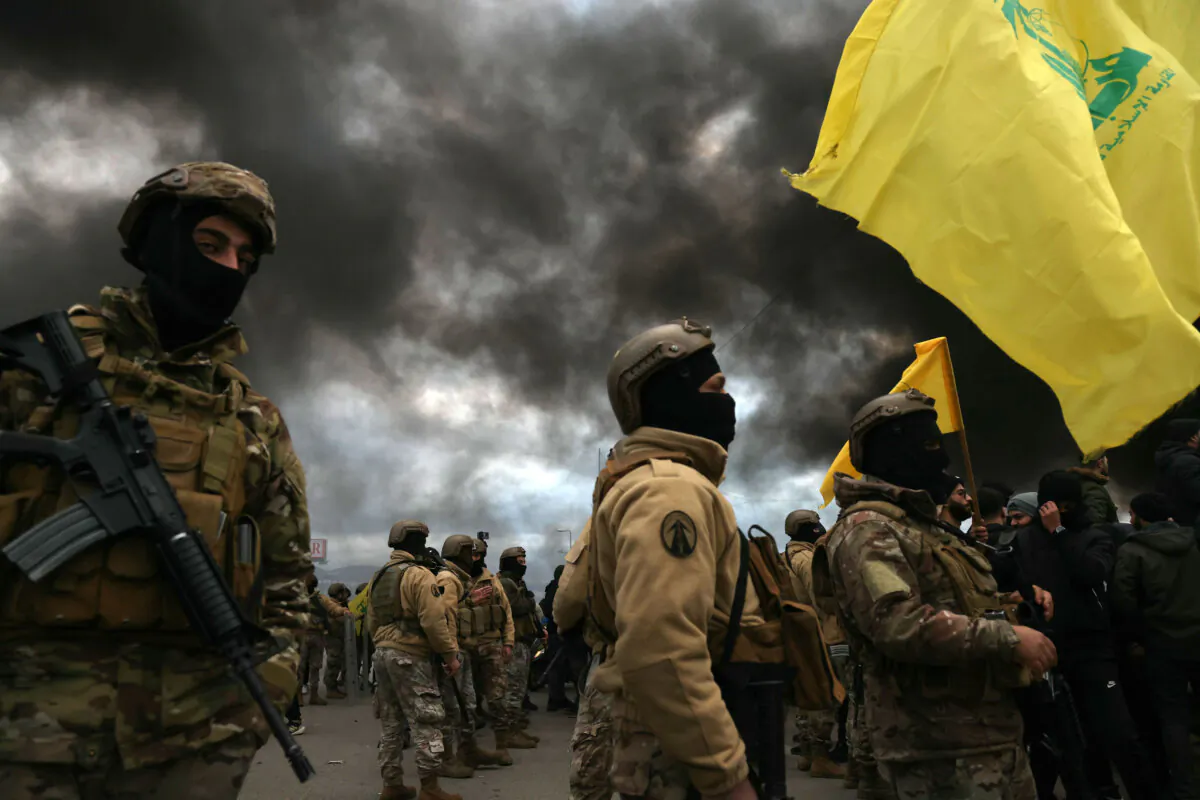 Hezbollah supporters wave the group's flag in front of Lebanese army troops, as protesters burn tires to block the road leading to Beirut's international airport, following the visit of U.S. Deputy Special Envoy for the Middle East Morgan Ortagus, during which she met with the country's president, on Feb. 7, 2025. (Ibrahim Amro/AFP via Getty Images)