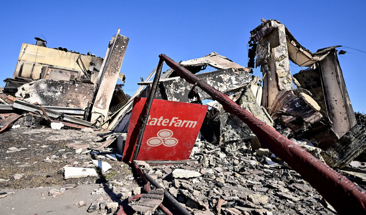 A State Farm insurance company sign sits amid the rubble of a building destroyed by the Palisades Fire on Sunset Boulevard in the Pacific Palisades neighborhood of Los Angeles on January 16, 2025. Tens of thousands of people ordered to flee their homes as wildfires tore through Los Angeles were told on January 16 they would not be allowed back for at least a week, with fears over electrocution, landslides and exposure to toxic materials. (Photo by Frederic J. BROWN / AFP) (Photo by FREDERIC J. BROWN/AFP via Getty Images)