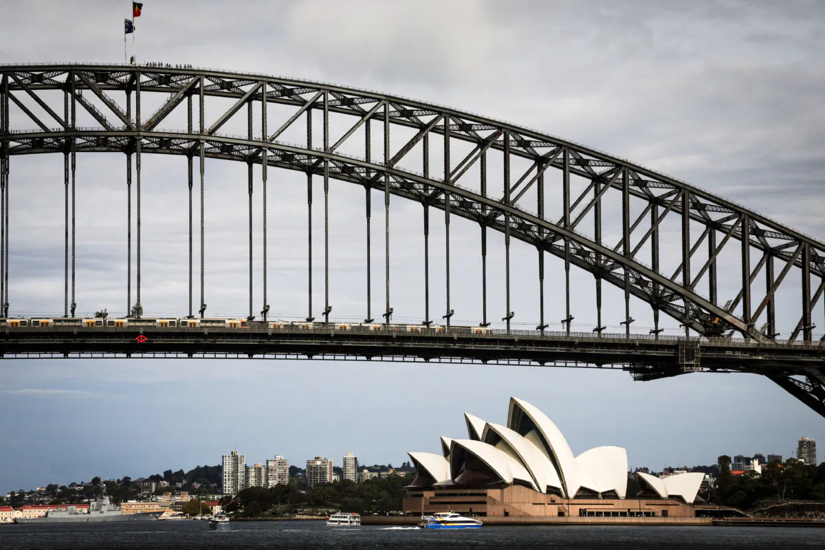 People stand atop of the Sydney Harbour Bridge as ferries sail past the Sydney Opera House during summer on February 11, 2025. (Photo by DAVID GRAY / AFP) (Photo by DAVID GRAY/AFP via Getty Images)