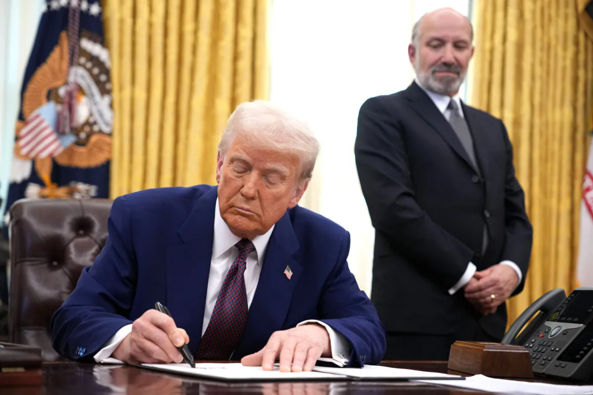 President Donald Trump, joined by Secretary of Commerce nominee Howard Lutnick, signs an executive order on reciprocal tariffs in the Oval Office of the White House in Washington on Feb. 13, 2025. (Andrew Harnik/Getty Images)