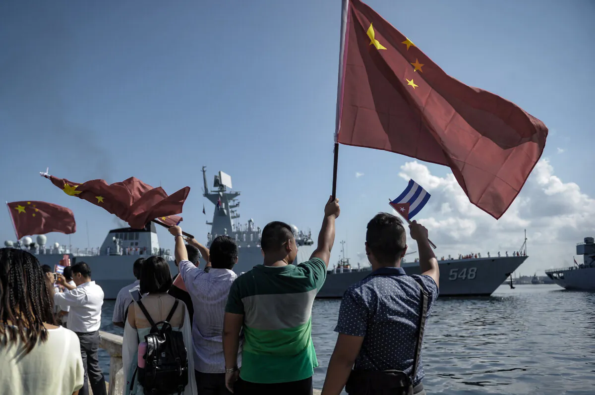 People wave Cuban and PRC flags as several Chinese Navy vessels enter the port of Havana on Nov. 10, 2015. (Yamil Lage/AFP via Getty Images)