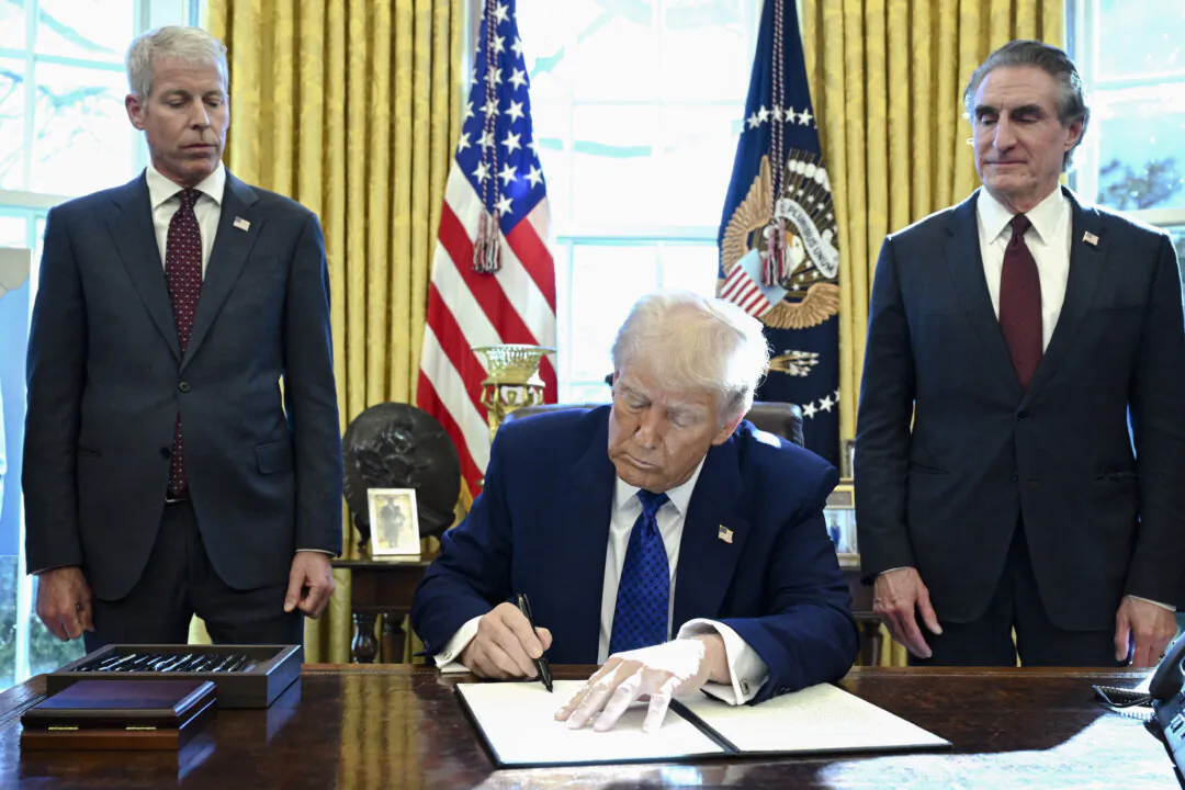 President Donald Trump, with Secretary of Energy Chris Wright (L) and Secretary of the Interior Doug Burgum (R), signs an executive order on halting federal funds for schools and universities that impose coronavirus vaccine mandates in the Oval Office of the White House on Feb. 14, 2025. (Saul Loeb/AFP via Getty Images)