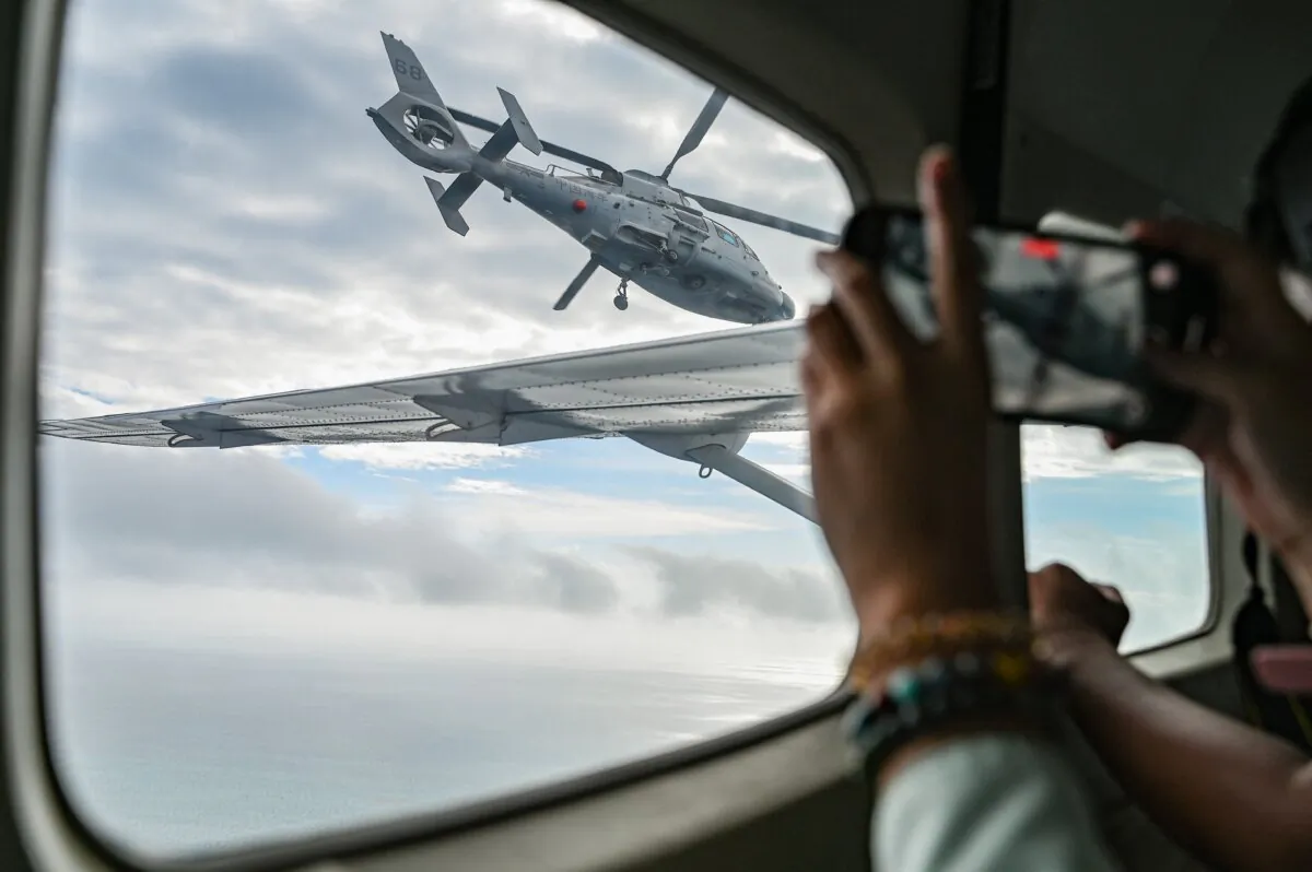 An aircraft identified by the Philippine Coast Guard as a Chinese navy helicopter (L) flies near the Bureau of Fisheries and Aquatic Resources (BFAR) plane during an aerial reconnaissance flight at Scarborough Shoal in the South China Sea on Feb. 18, 2025. (Jam Sta Rosa/AFP via Getty Images)
