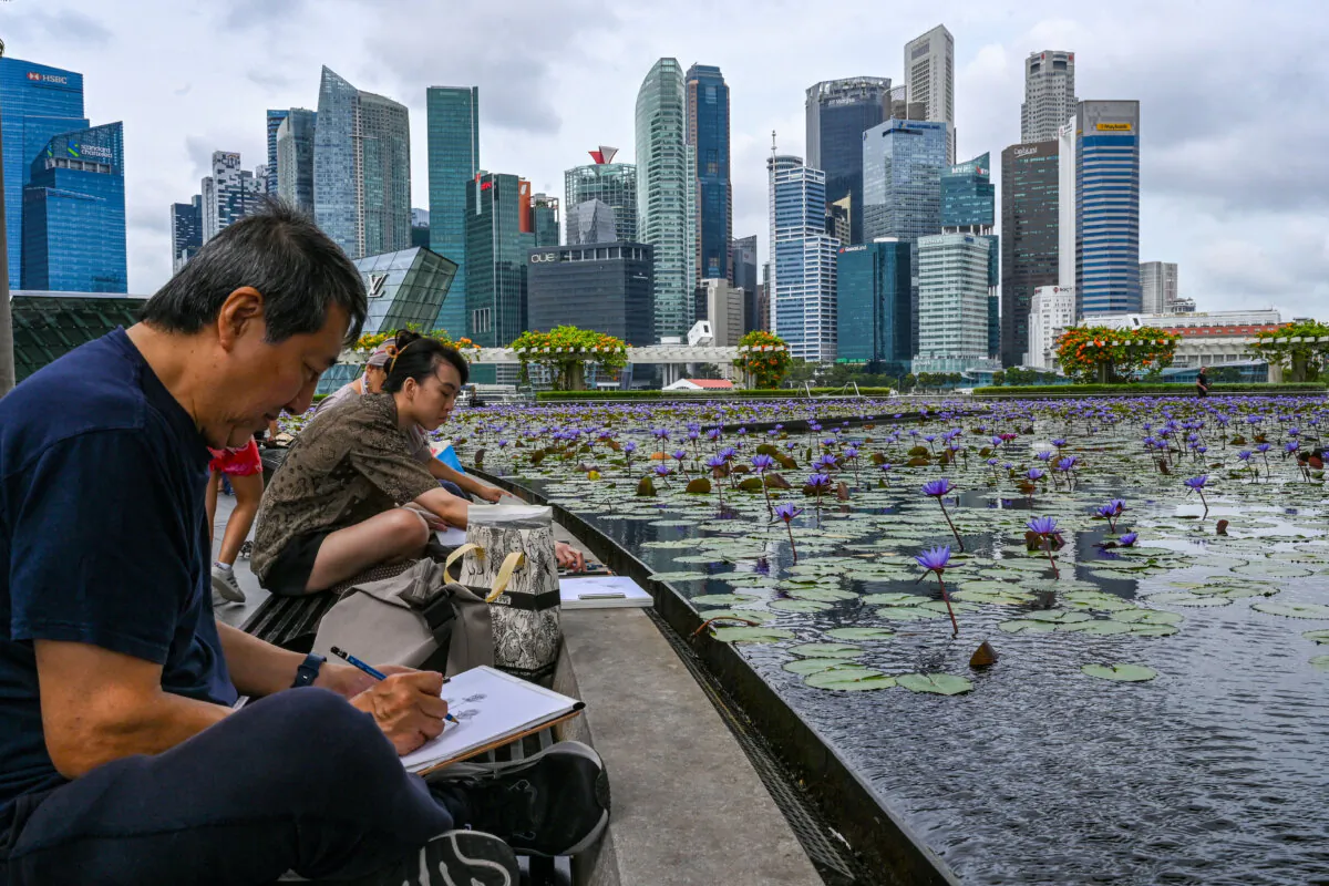 Artists make drawings by a pond outside the ArtScience Museum next to the city skyline in Singapore on Feb. 18, 2025. (Roslan Rahman/AFP via Getty Images)