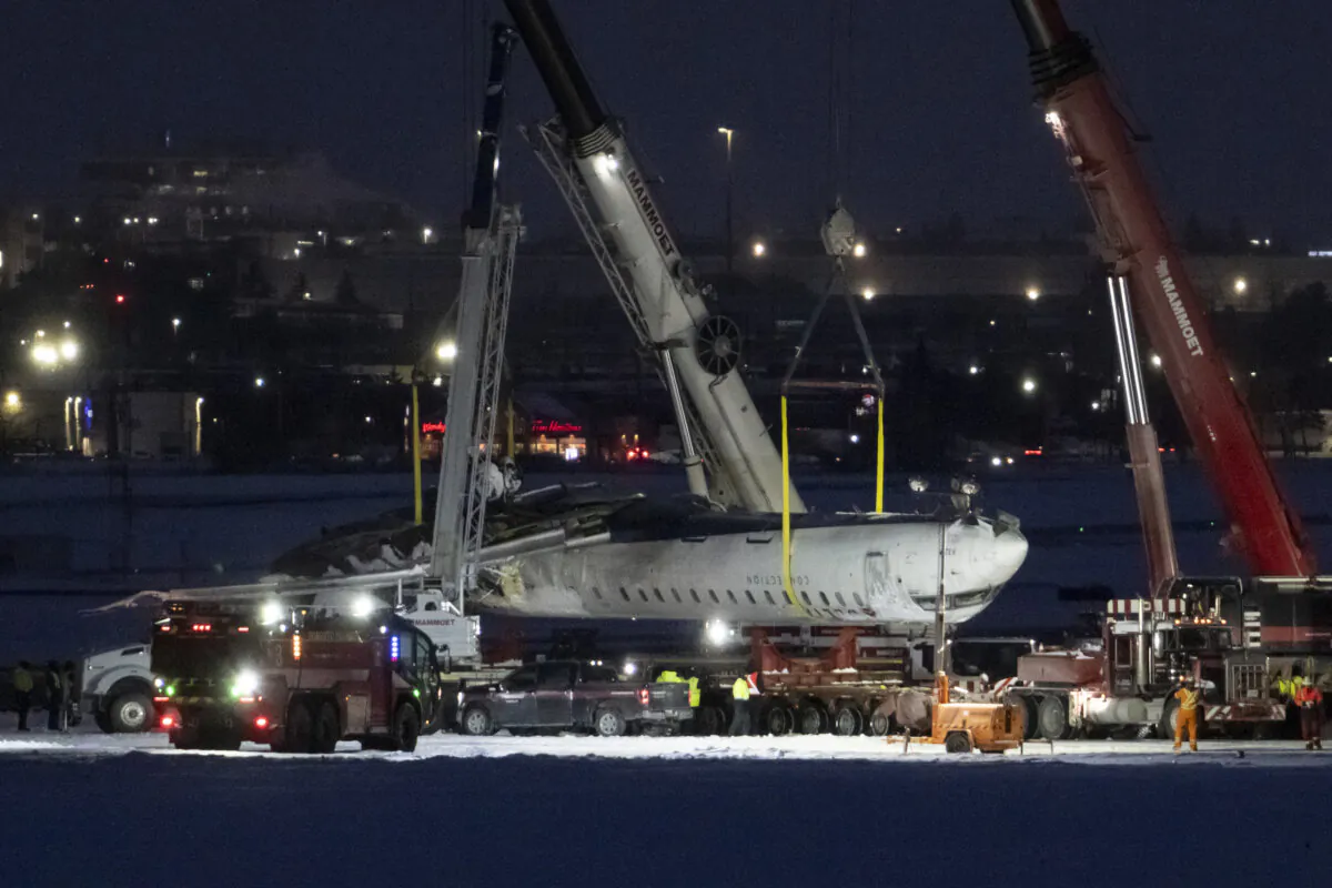 Cranes lift the wreckage of Delta Flight 4819 from the runway onto a truck at Toronto Pearson International Airport, in Mississauga, Ont., on Feb. 19, 2025. (The Canadian Press/Arlyn McAdorey)
