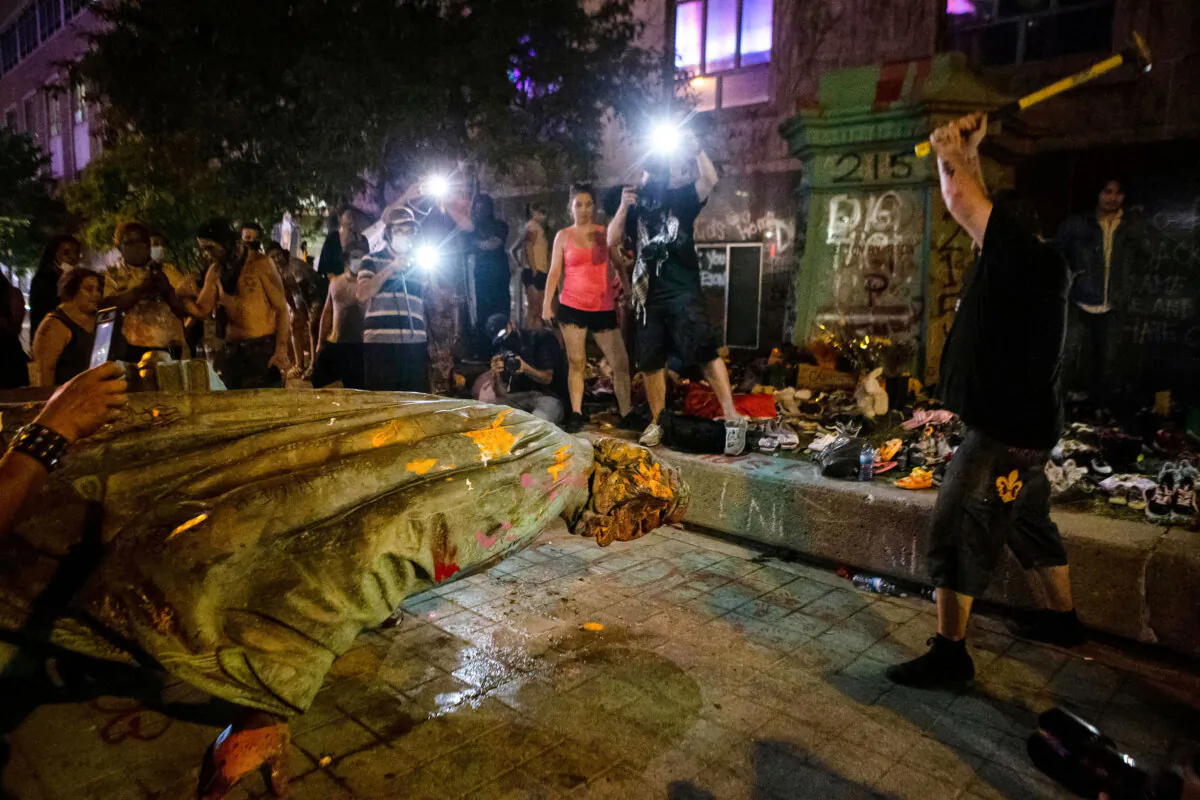 A protester swings a hammer in an attempt to remove the head of the just-toppled Egerton Ryerson statue in Toronto on June 6, 2021. (The Canadian Press/Chris Young)