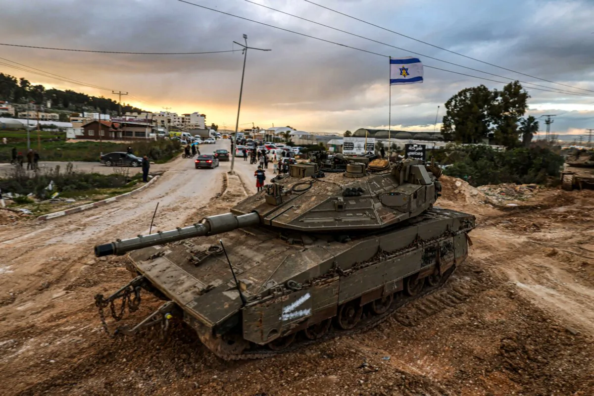 People look on as Israeli tanks enter the Jenin camp for Palestinian refugees in the West Bank on Feb. 23, 2025. (Jaafar Ashtiyeh/AFP via Getty Images)