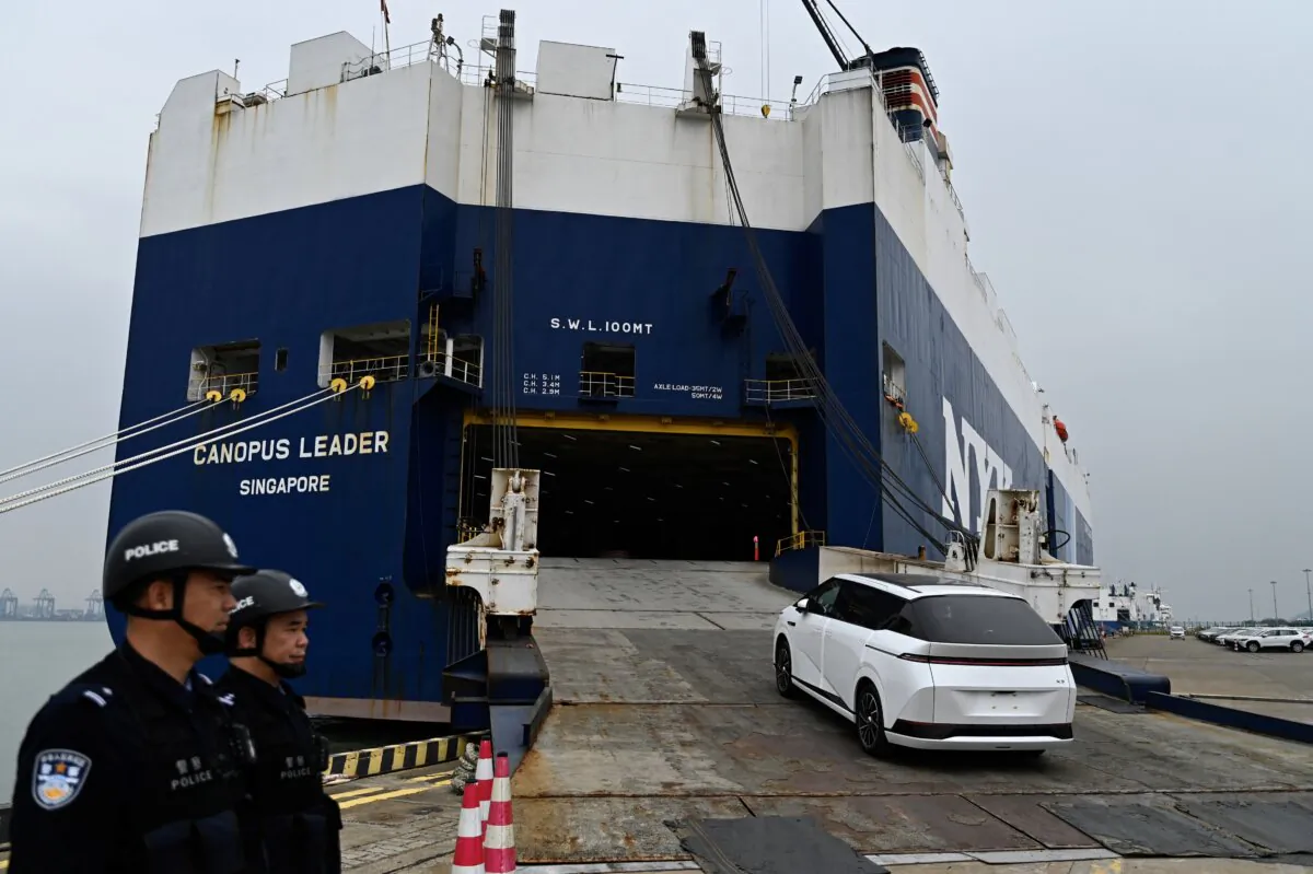 Security officers watch an XPeng X9 electric vehicle being loaded onto a ship bound for Thailand in Guangzhou, China, on Feb. 22, 2025. (Pedro Pardo/AFP via Getty Images)
