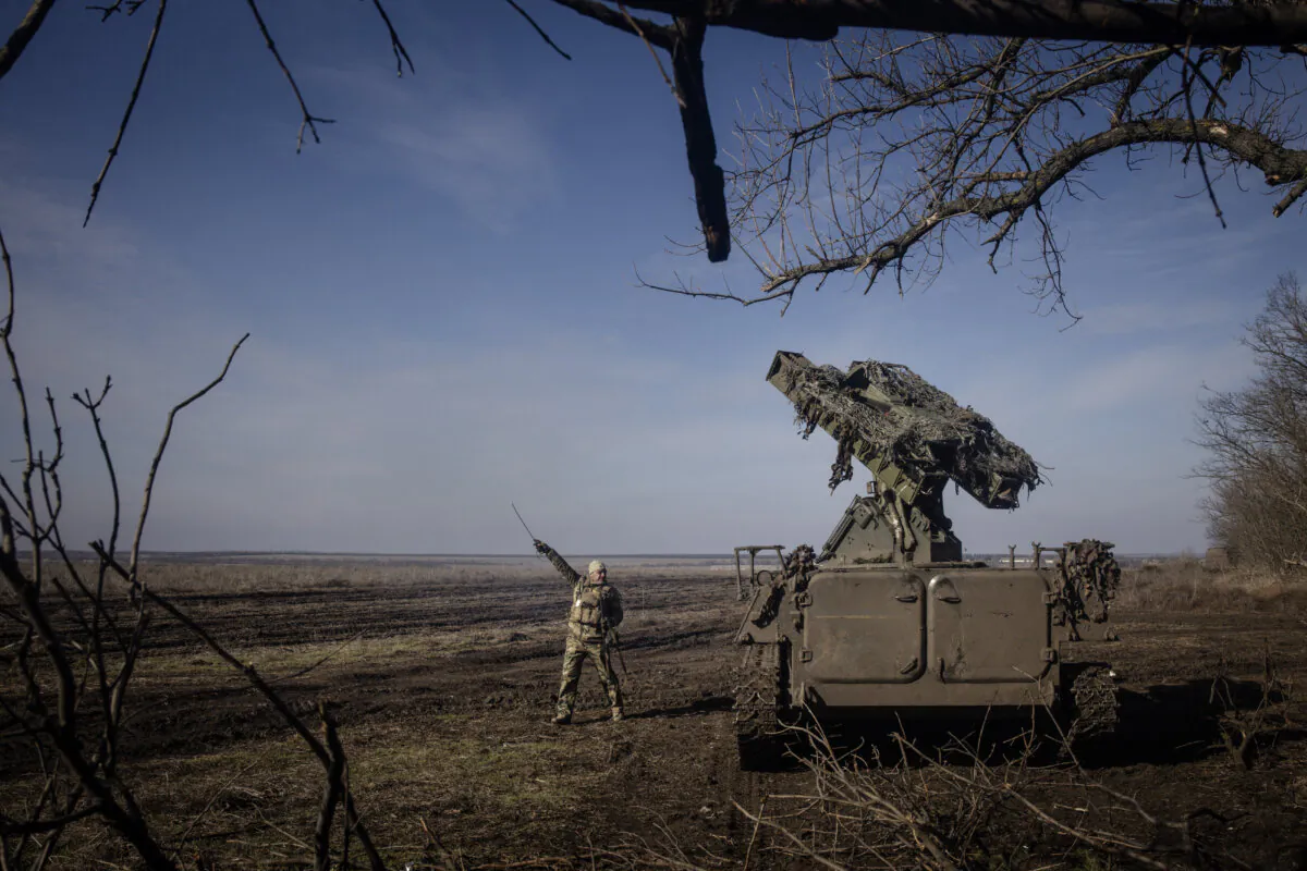 A member of Ukraine's 72nd Brigade anti-air unit points in the direction of a Russian Zala reconnaissance drone sighted overhead as they prepare to fire a Strela-10 anti-air missile system near Marinka, Ukraine, on Feb. 23, 2024. (Chris McGrath/Getty Images)