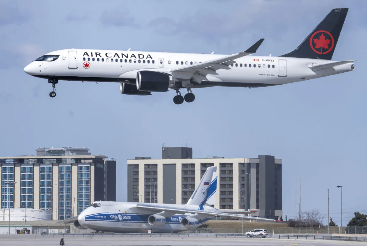 An Air Canada flight lands in front of a Russian-registered Antonov AN-124 owned by Volga-Dneper at Pearson Airport in Toronto, on March 21, 2022. (The Canadian Press/Frank Gunn) 
