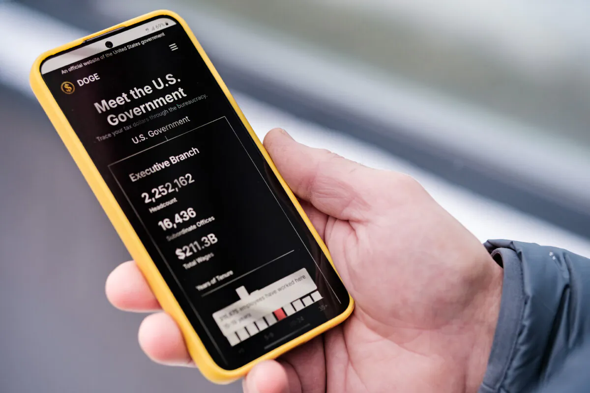 The Department of Government Efficiency (DOGE) website is displayed on a cellphone. (Oleksii Pydsosonnii/The Epoch Times)