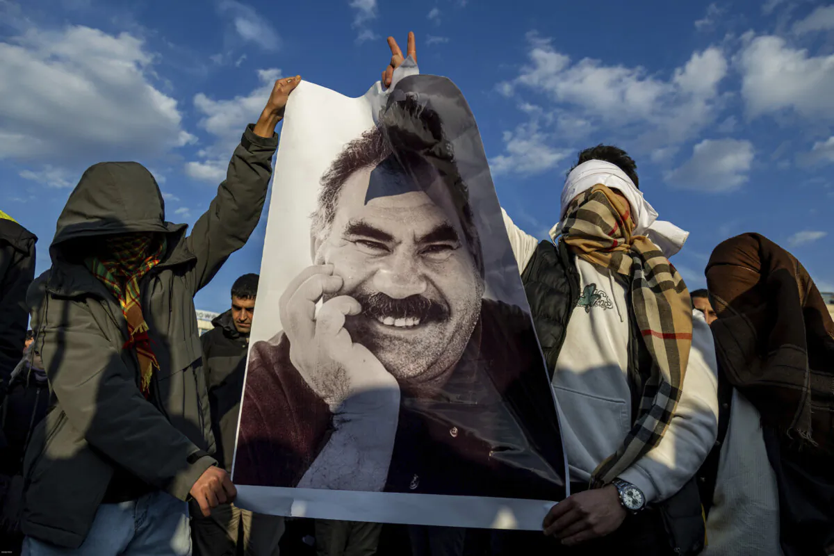 Young people hold a photograph of the jailed leader of the Kurdistan Workers' Party, Abdullah Ocalan, as they gather to watch a live reading of his statement in Diyarbakir, Turkey, on Feb. 27, 2025. (Metin Yoksu/AP)