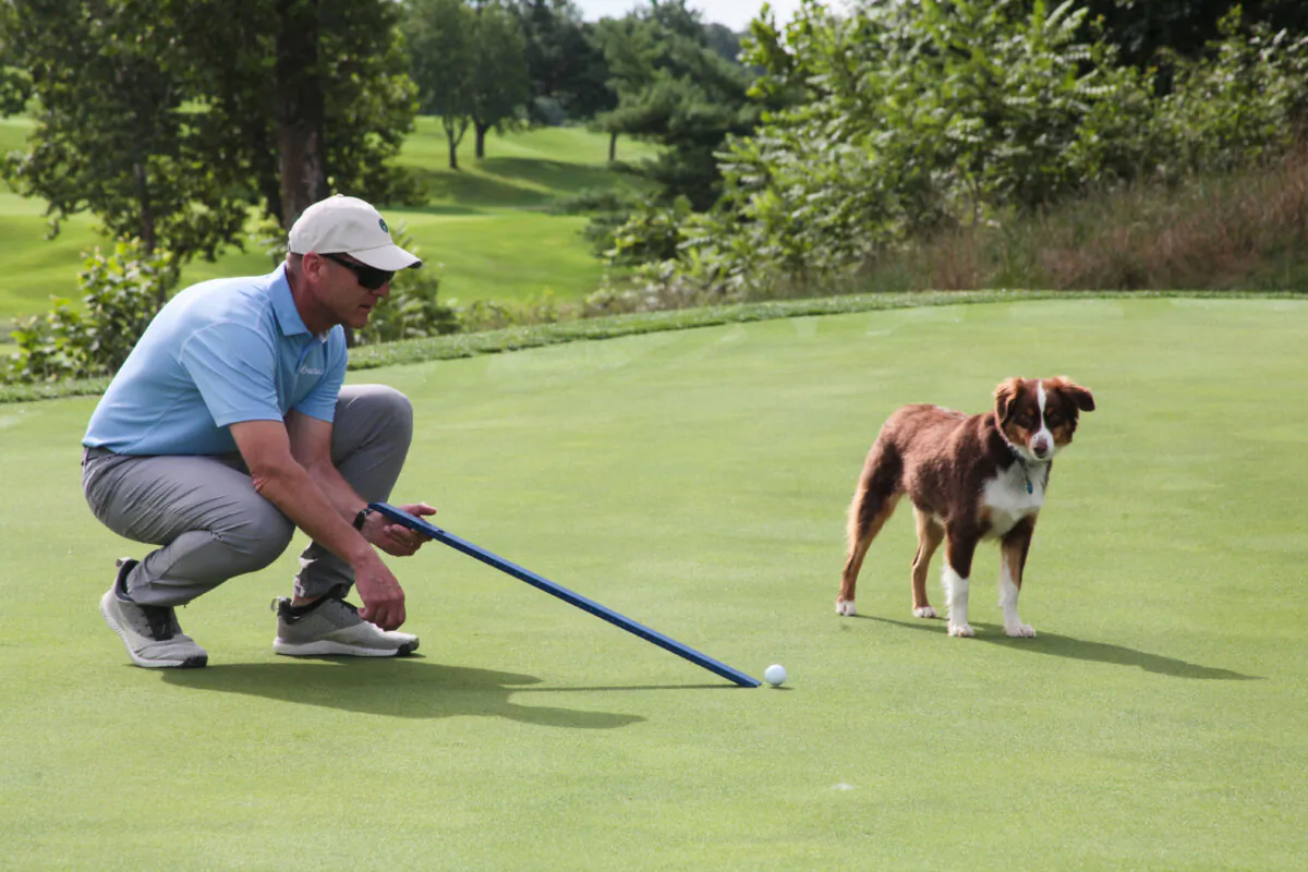 A superintendent uses a stimpmeter on a golf course with his dog in Kansas City, Mo., in 2022. (Courtesy of GCSAA)