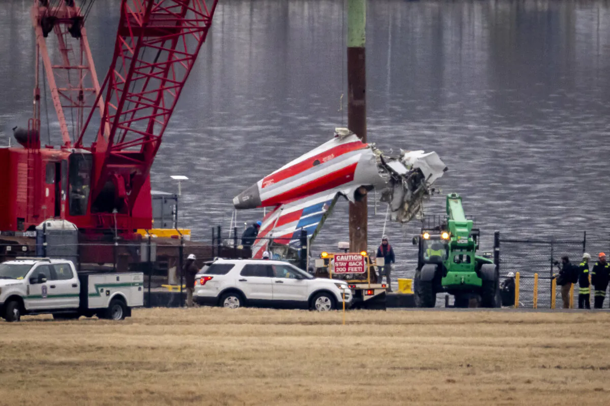 A crane offloads a piece of wreckage from a salvage vessel onto a flatbed truck, near the wreckage site in the Potomac River of a mid-air collision between an American Airlines jet and a Black Hawk helicopter, at Ronald Reagan Washington National Airport, Wednesday, Feb. 5, 2025, in Arlington, Va. (Ben Curtis/AP Photo)