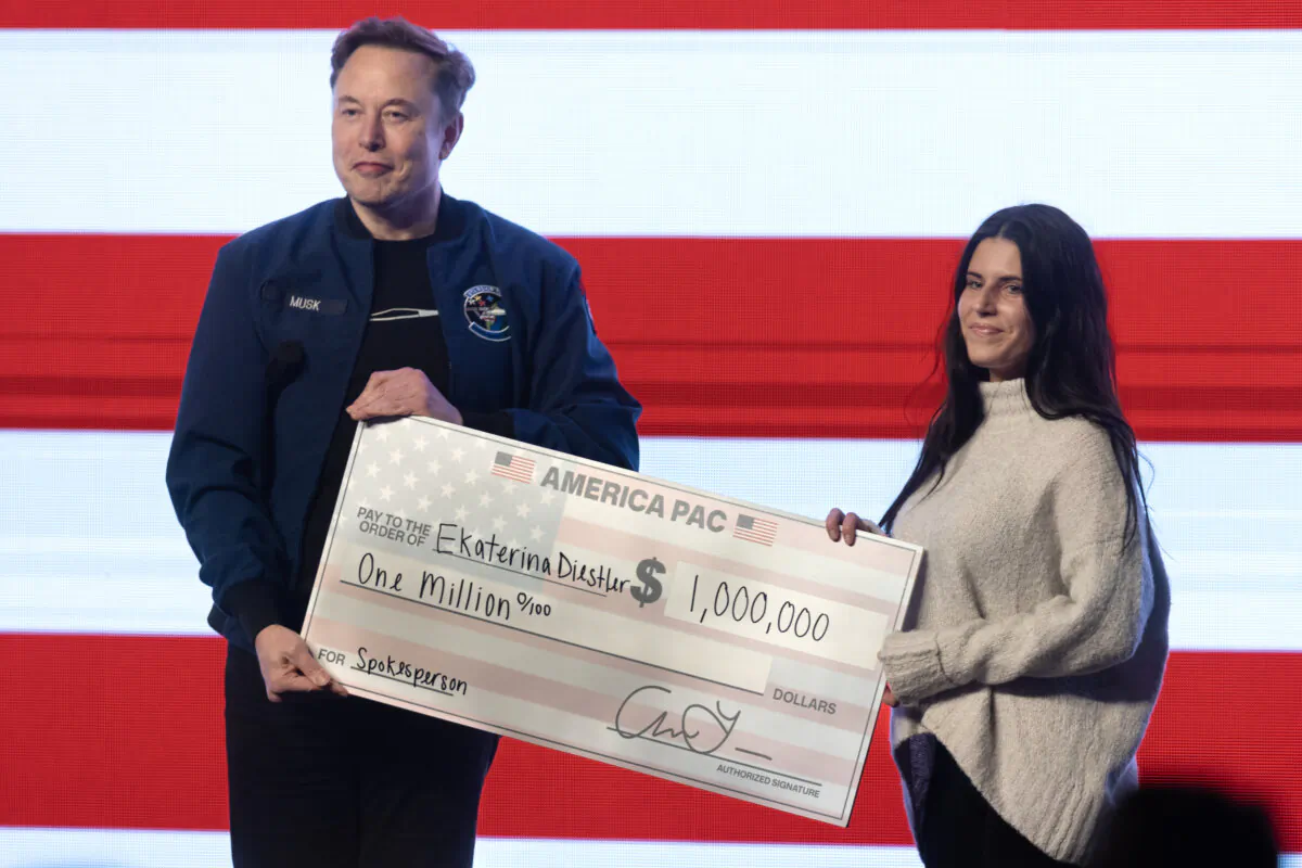 Billionaire businessman Elon Musk gives $1,000,000 to a Wisconsin voter, Ekaterina Diestler, during a town hall meeting he was hosting at the KI Convention Center in Green Bay, Wis., on March 30, 2025. (Scott Olson/Getty Images)