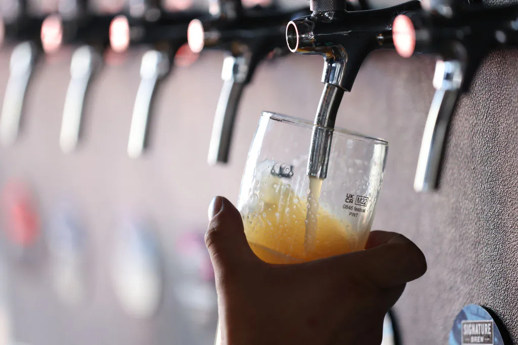 A bartender pours a beer from a tap. (HOLLIE ADAMS/AFP via Getty Images)