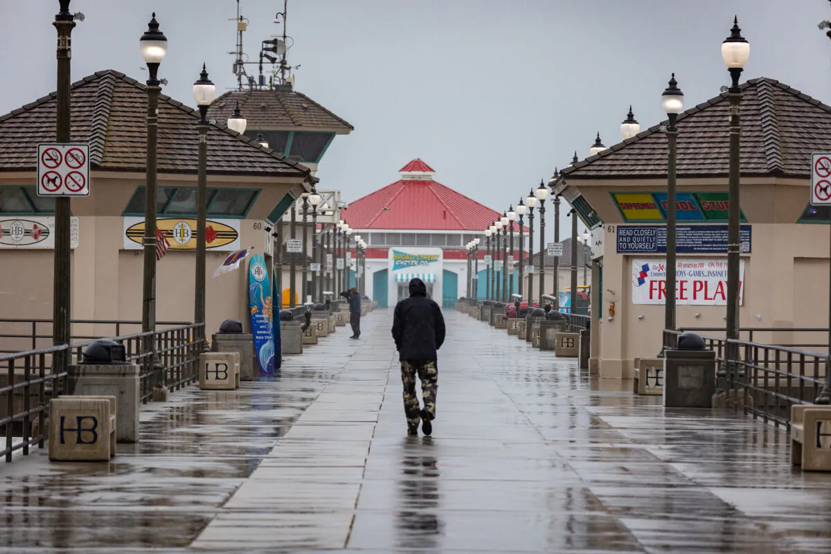 A man walks in a rain storm in Huntington Beach, Calif., on Feb. 20, 2024. (John Fredricks/The Epoch Times)