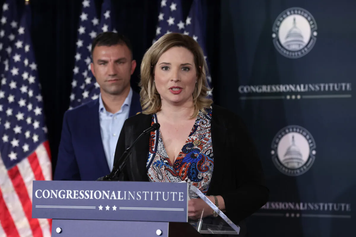 U.S. Rep. Ashley Hinson (R-Iowa) (R) speaks to members of the press as Rep. Rudy Yakym (R-Ind.) listens, at the Greenbrier Hotel in White Sulphur Springs, W. Va., on March 14, 2024. (Alex Wong/Getty Images)