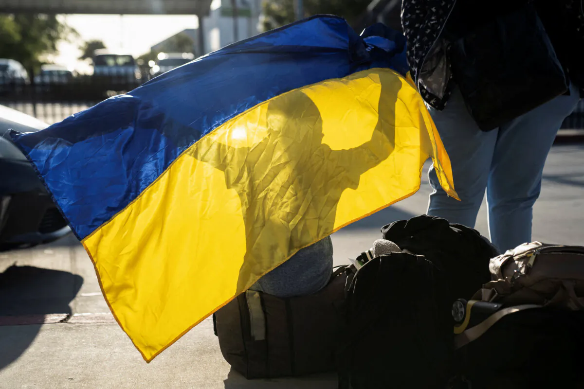 A Ukrainian boy seeking asylum in the United States plays with a Ukrainian flag after arriving at the PedWest border crossing at the San Ysidro Port of Entry in San Diego, Calif., on April 13, 2022. (Reuters)