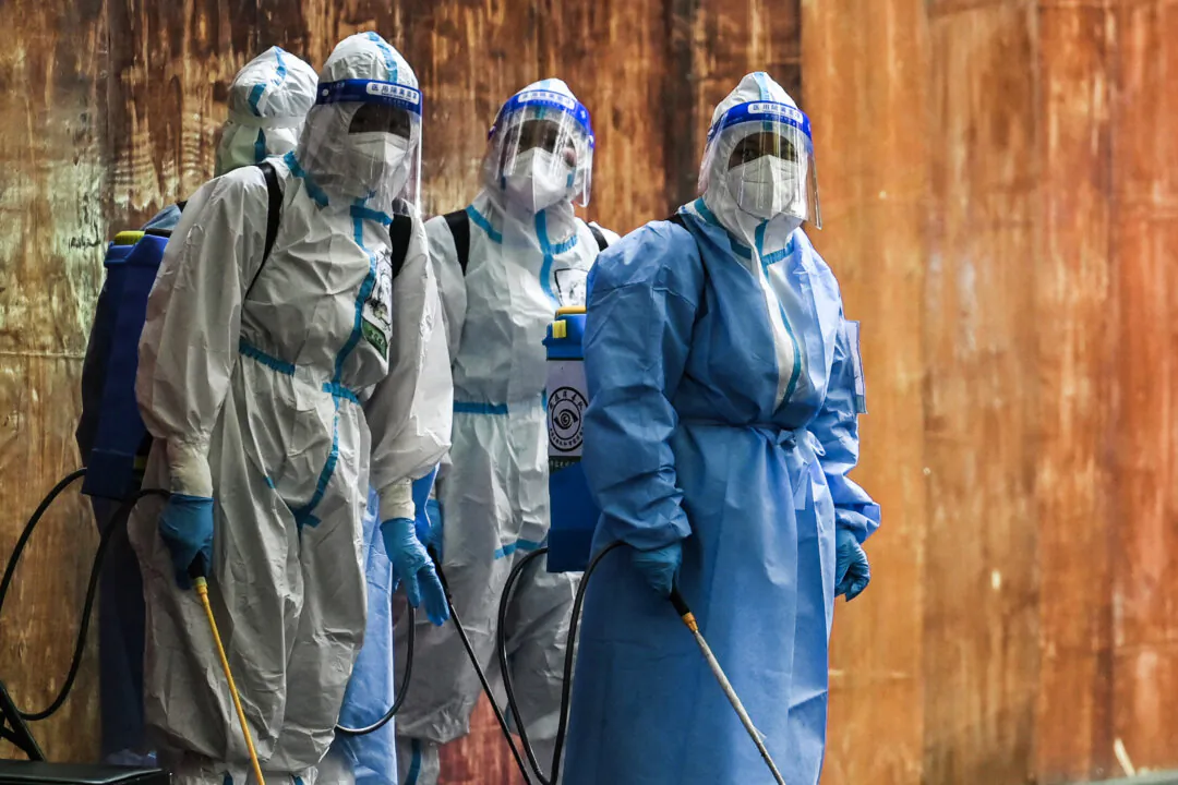 Workers who handle disinfectant look on next to a residential area under a COVID-19 pandemic lockdown in the Huangpu district of Shanghai, on June 4, 2022. (Hector Retamal/AFP via Getty Images)