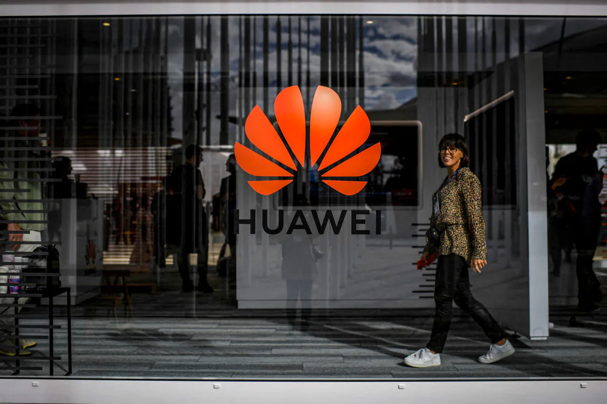 A woman walks past the logo of Chinese telecom giant, Huawei, during a web summit in Lisbon, Portugal, on Nov. 6, 2019. (Patricia de Melo Moreira/AFP via Getty Images)