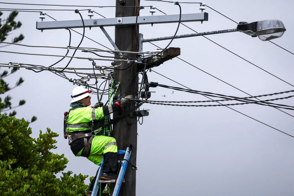 An electricity worker stands on a ladder as he works on electricity wires that were damaged due to strong winds from Cyclone Alfred in the suburb of Elanora on the Gold Coast on March 8, 2025. (DAVID GRAY/AFP via Getty Images)